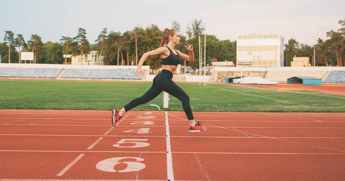 Fit woman in grey sports bra posing in a gym